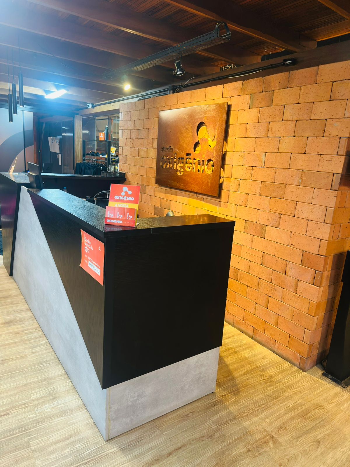 Recepção do Studio Oxigênio com logo em parede de tijolos, no Centro de Chapecó
